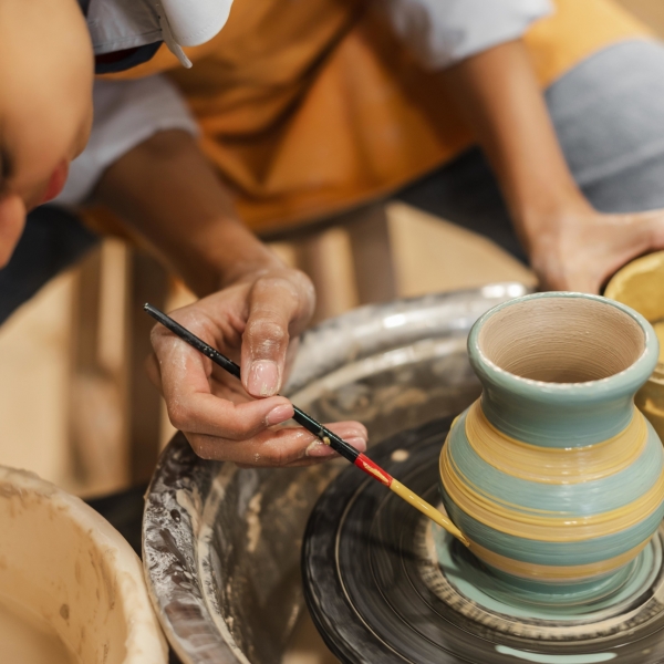 close-up-woman-painting-clay-pot
