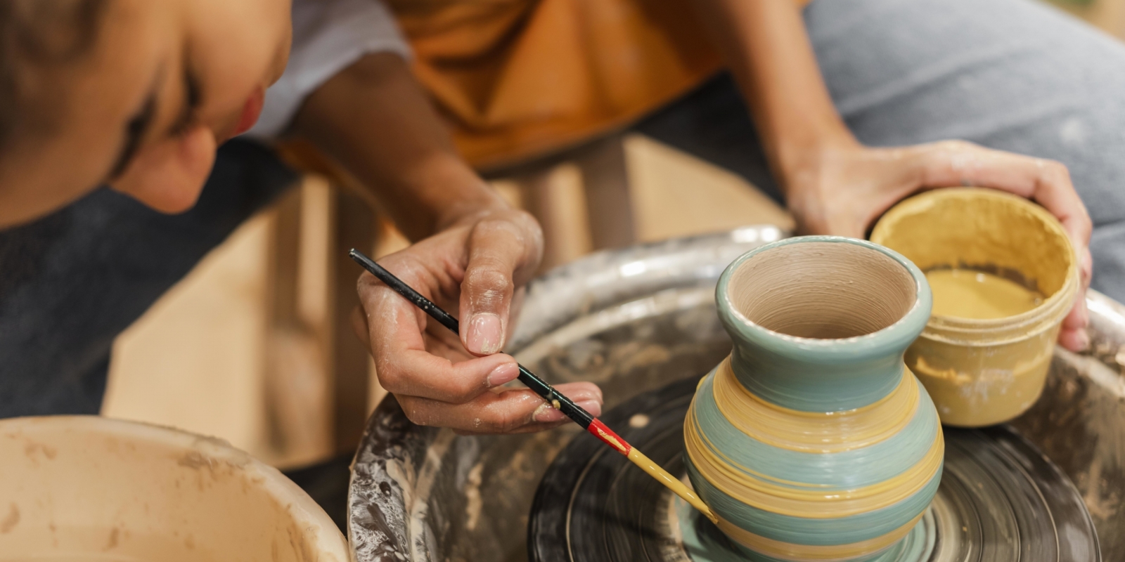 close-up-woman-painting-clay-pot